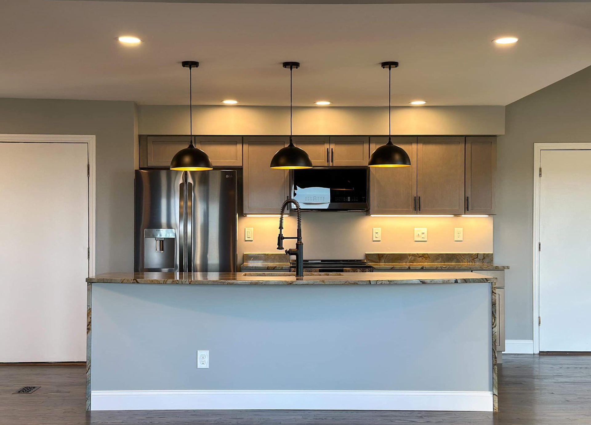 Modern kitchen with stainless steel appliances, pendant lights, and a large island counter