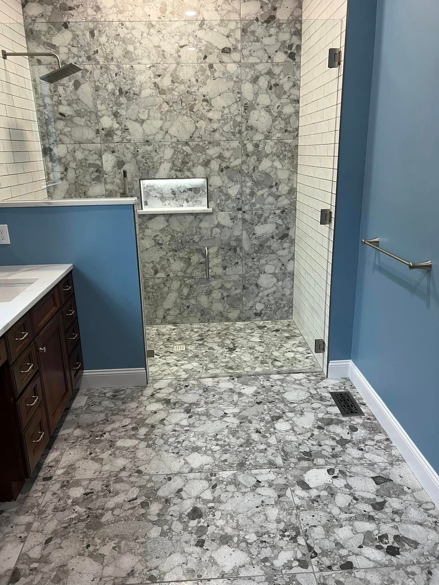 Accessible bathroom with blue walls, marble tile, and a wall-mounted toilet paper holder.