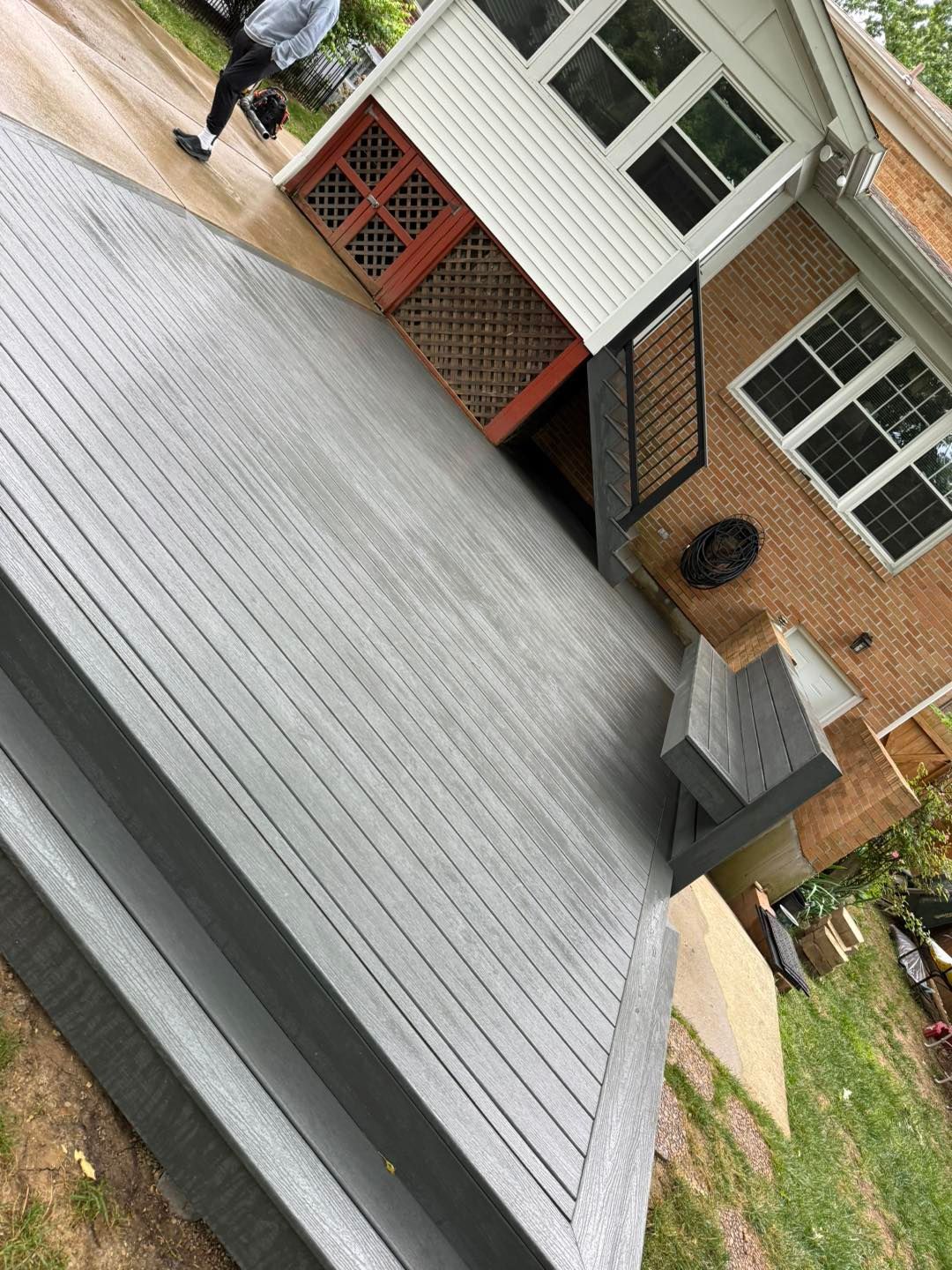 Close-up of a gray metal roof on a brick house with a white dormer and windows