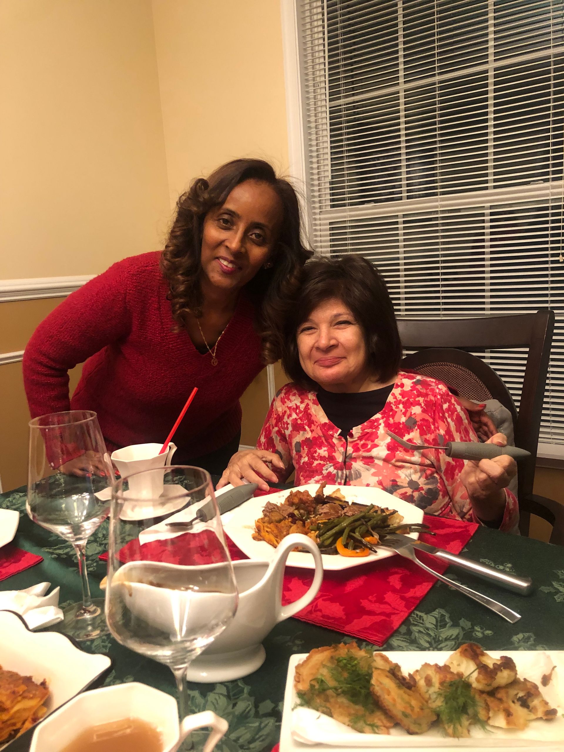 Three people seated on a deck talking, with food on the table.
