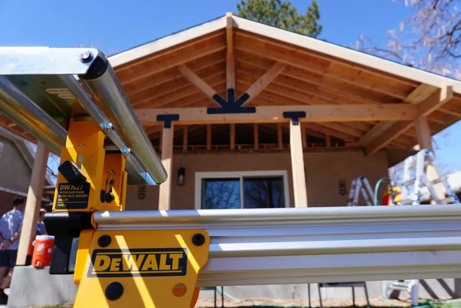 DeWalt saw in foreground, wooden structure with black brackets being built in backyard.