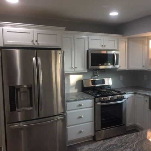 Modern kitchen with stainless steel appliances, white cabinets, and gray countertops