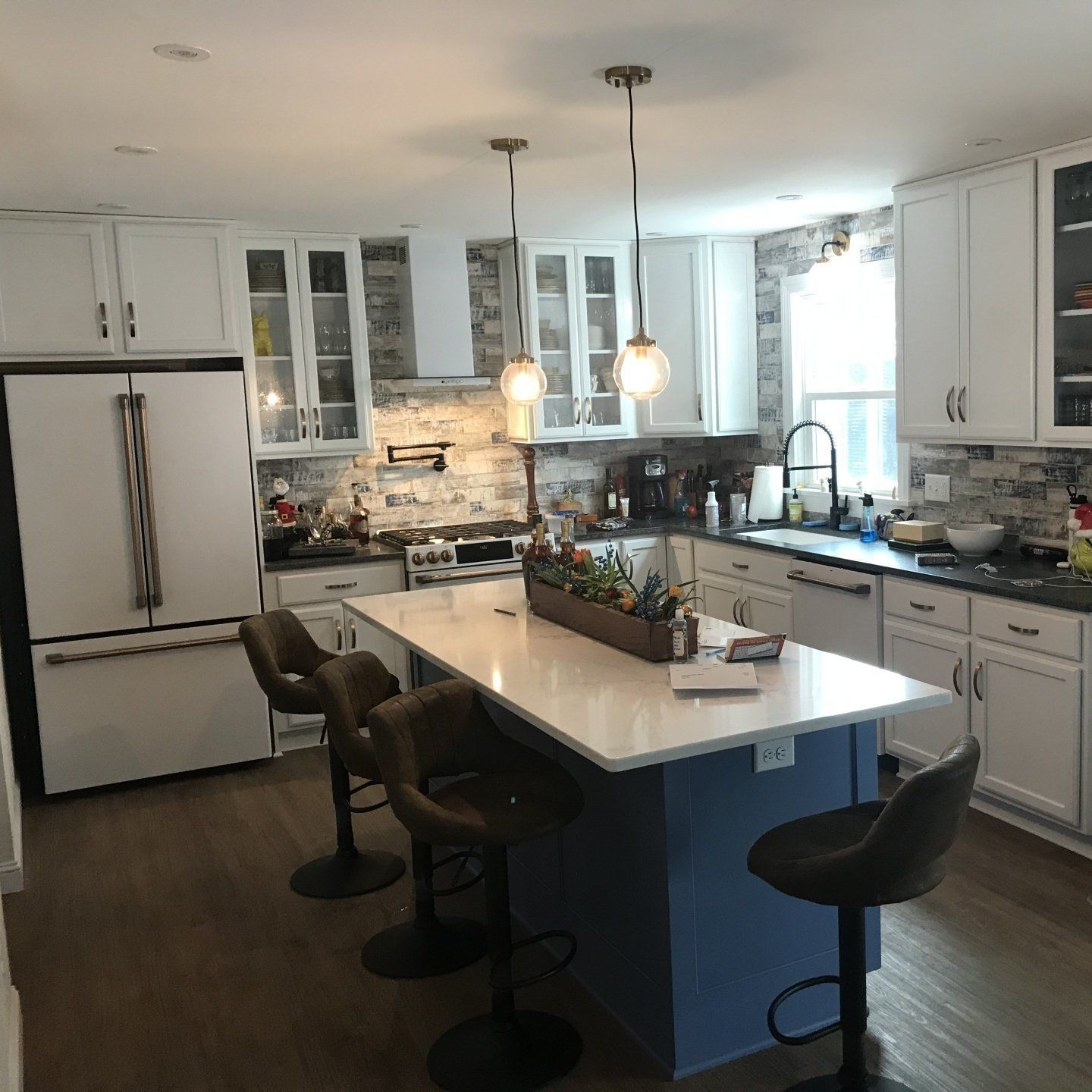 Bright modern kitchen with white cabinets, large island, pendant lights, and bar stools
