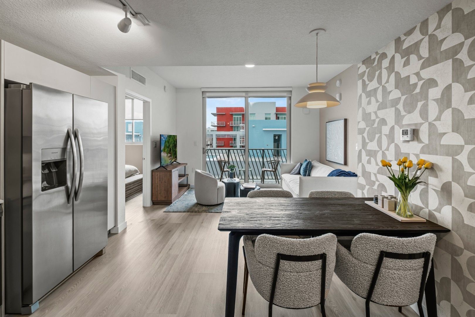 A living room with a dining table and chairs and a refrigerator.