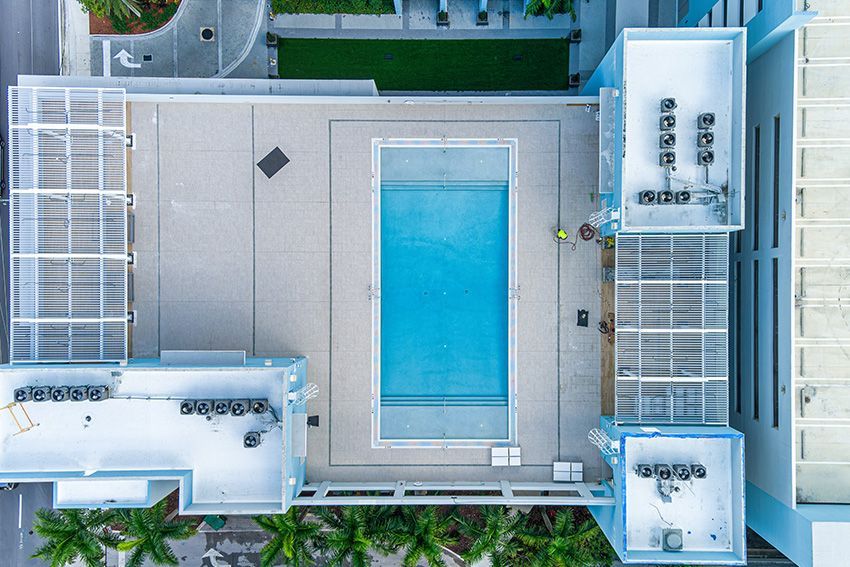 An aerial view of a large swimming pool surrounded by palm trees.