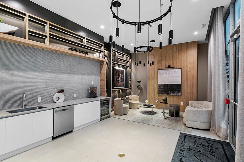 A kitchen with a sink , dishwasher , chairs and a television.