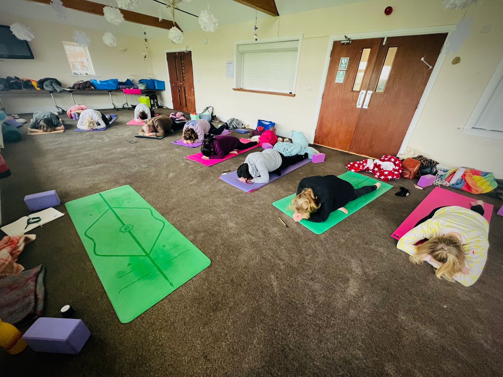 A room with people in a yoga position known as pigeon pose