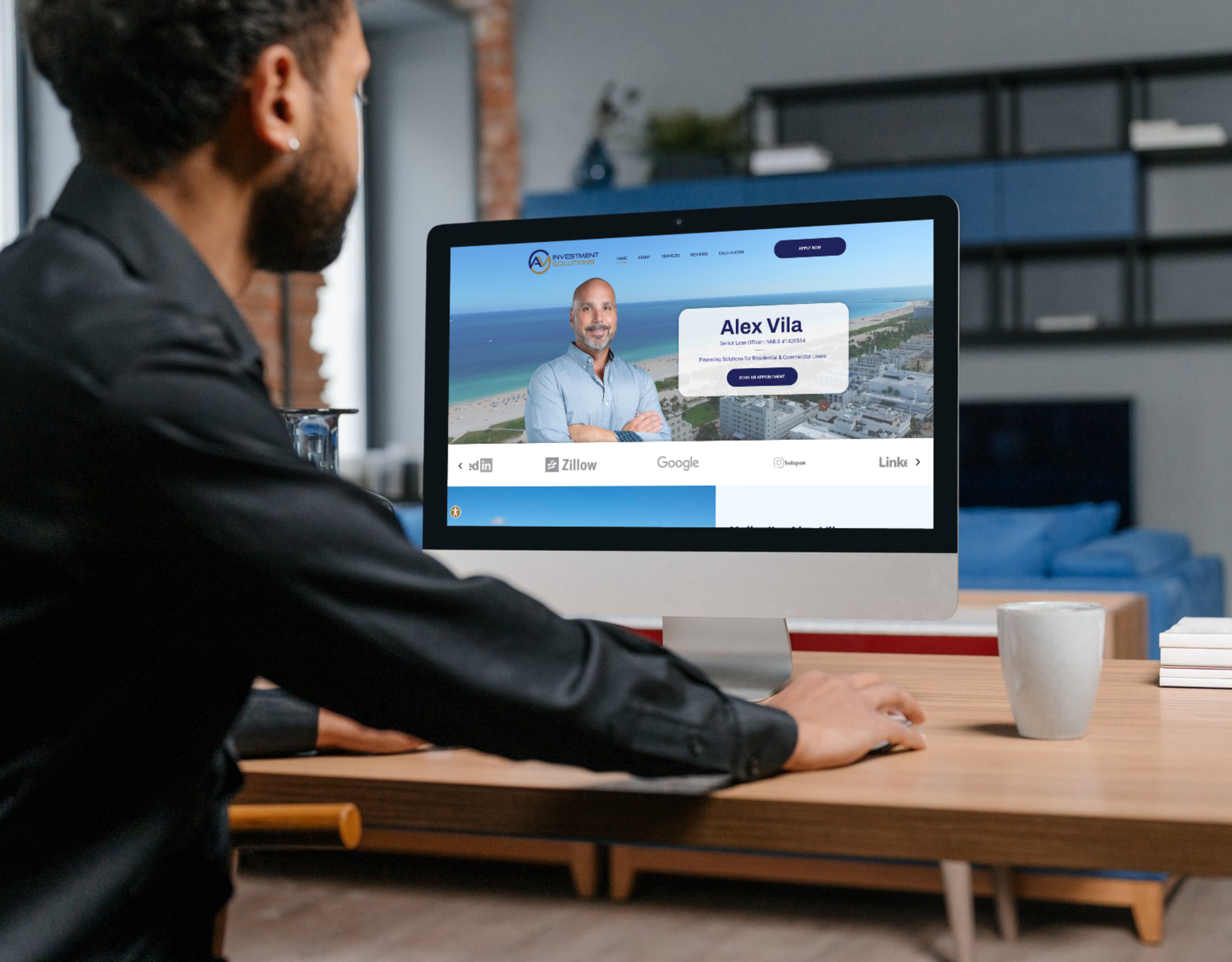 A man is sitting at a desk looking at a computer screen.
