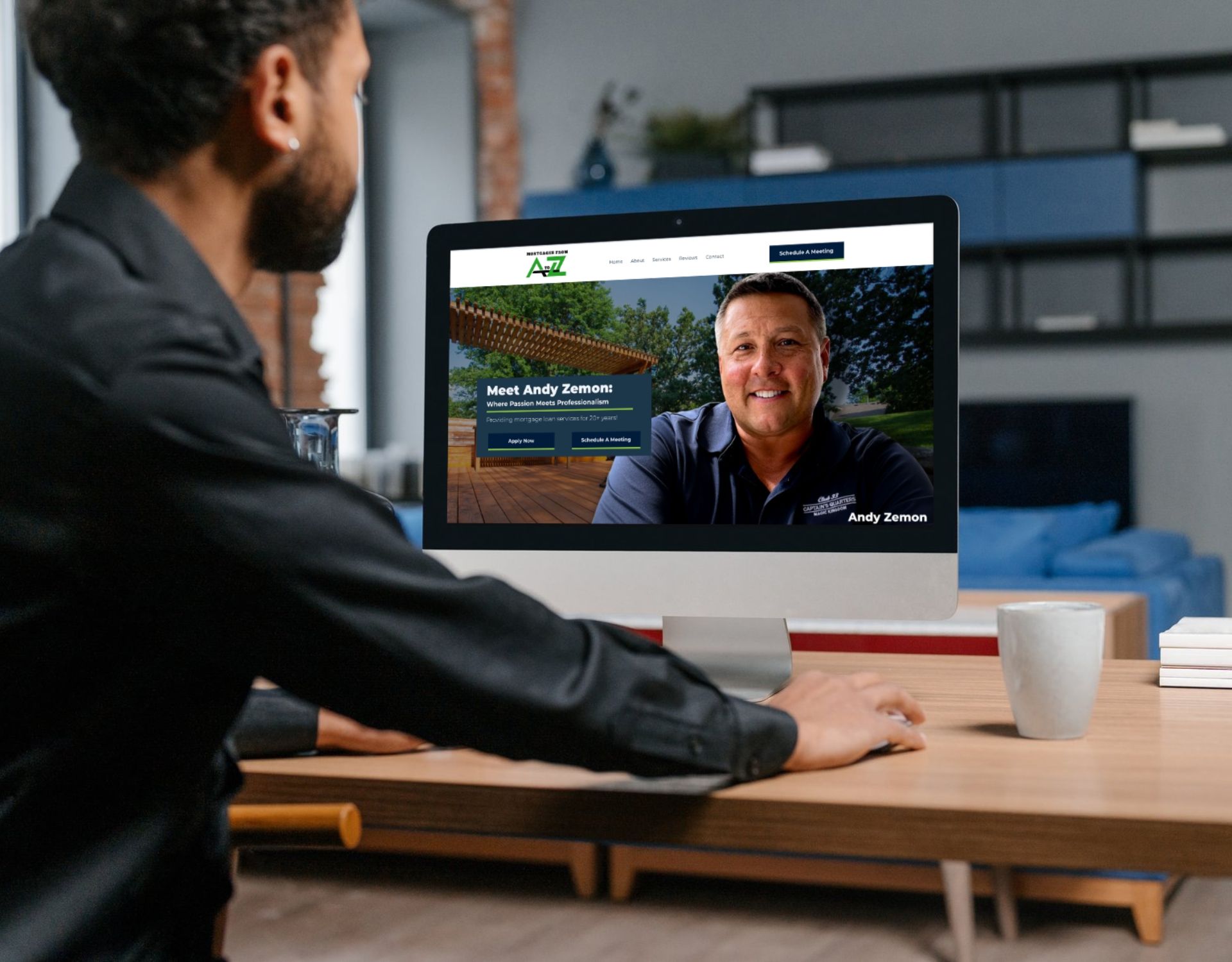 A man is sitting at a desk looking at a computer screen.