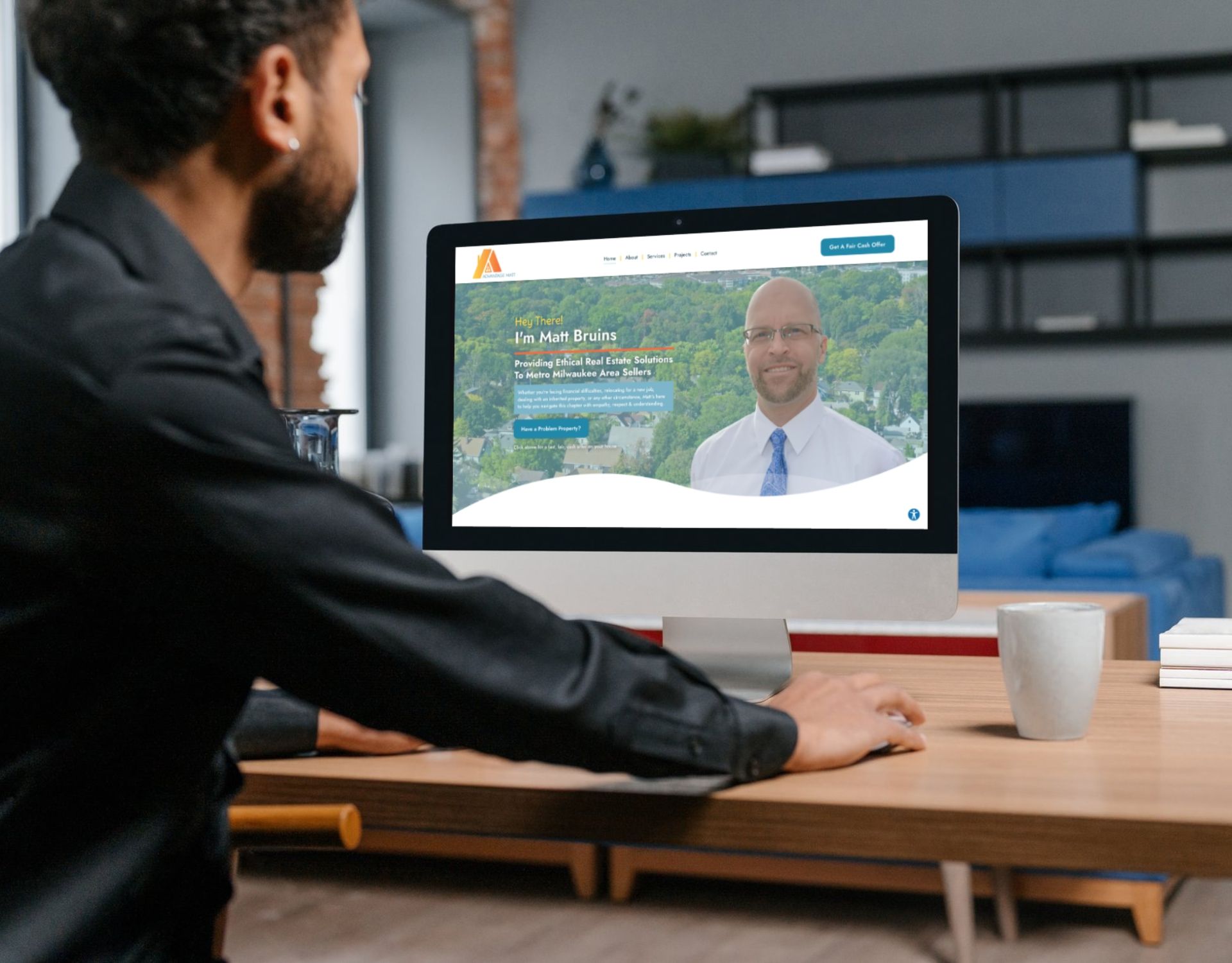 A man is sitting at a desk looking at a computer screen.