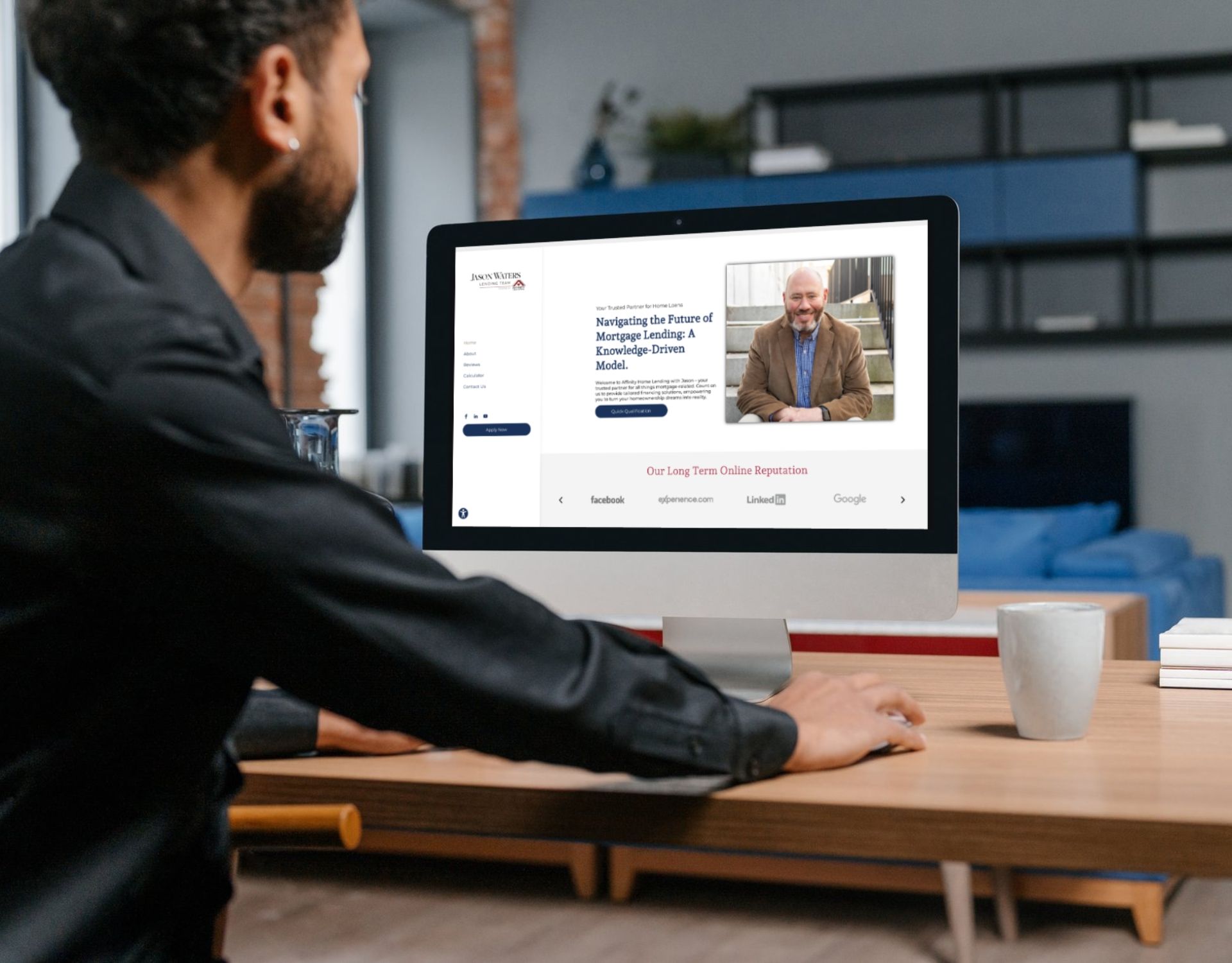A man is sitting at a desk looking at a computer screen.