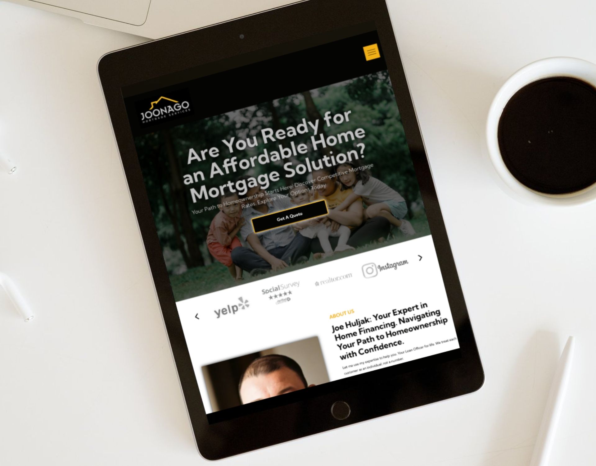 A tablet is sitting on a table next to a cup of coffee.