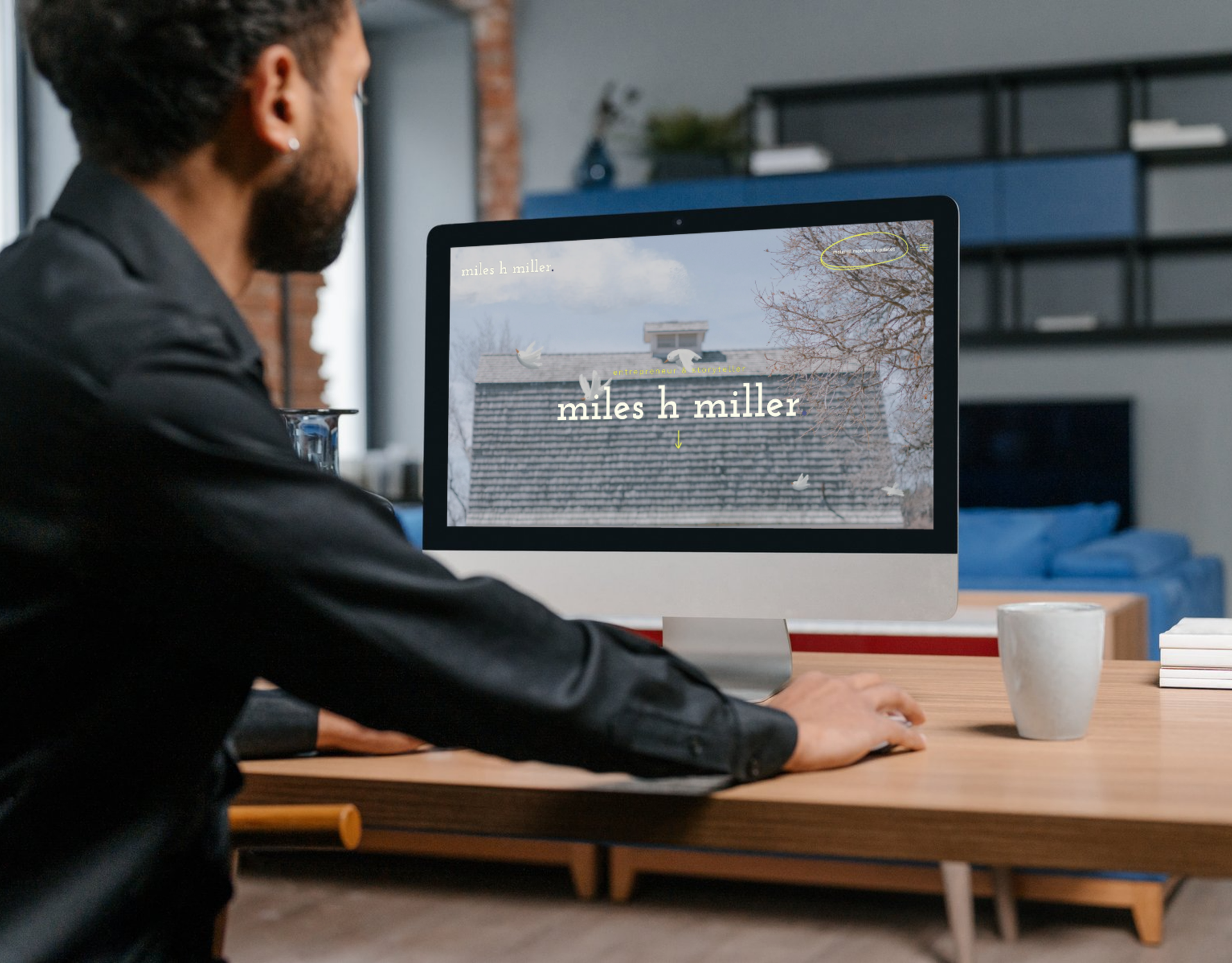 A man is sitting at a desk looking at a computer screen.