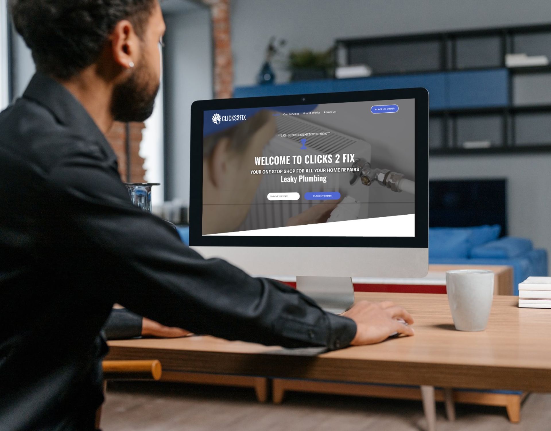A man is sitting at a desk looking at a computer screen.
