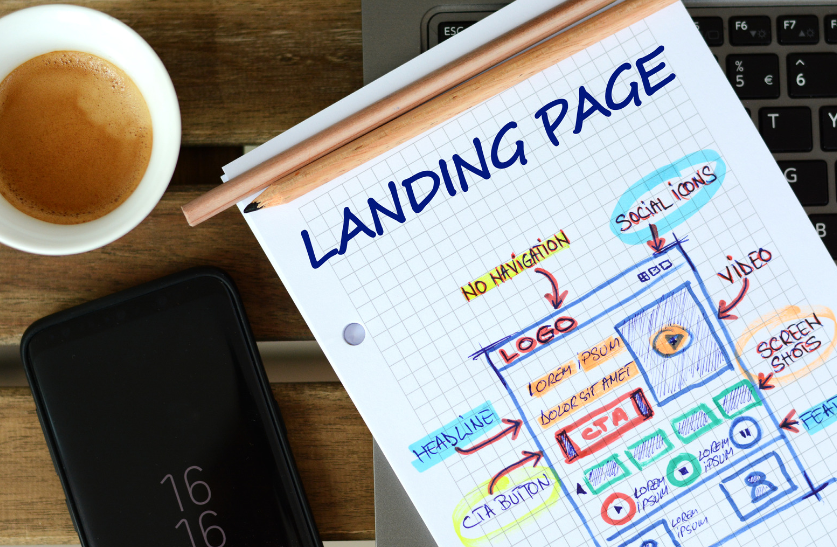 A landing page is being drawn on a piece of paper next to a cup of coffee.