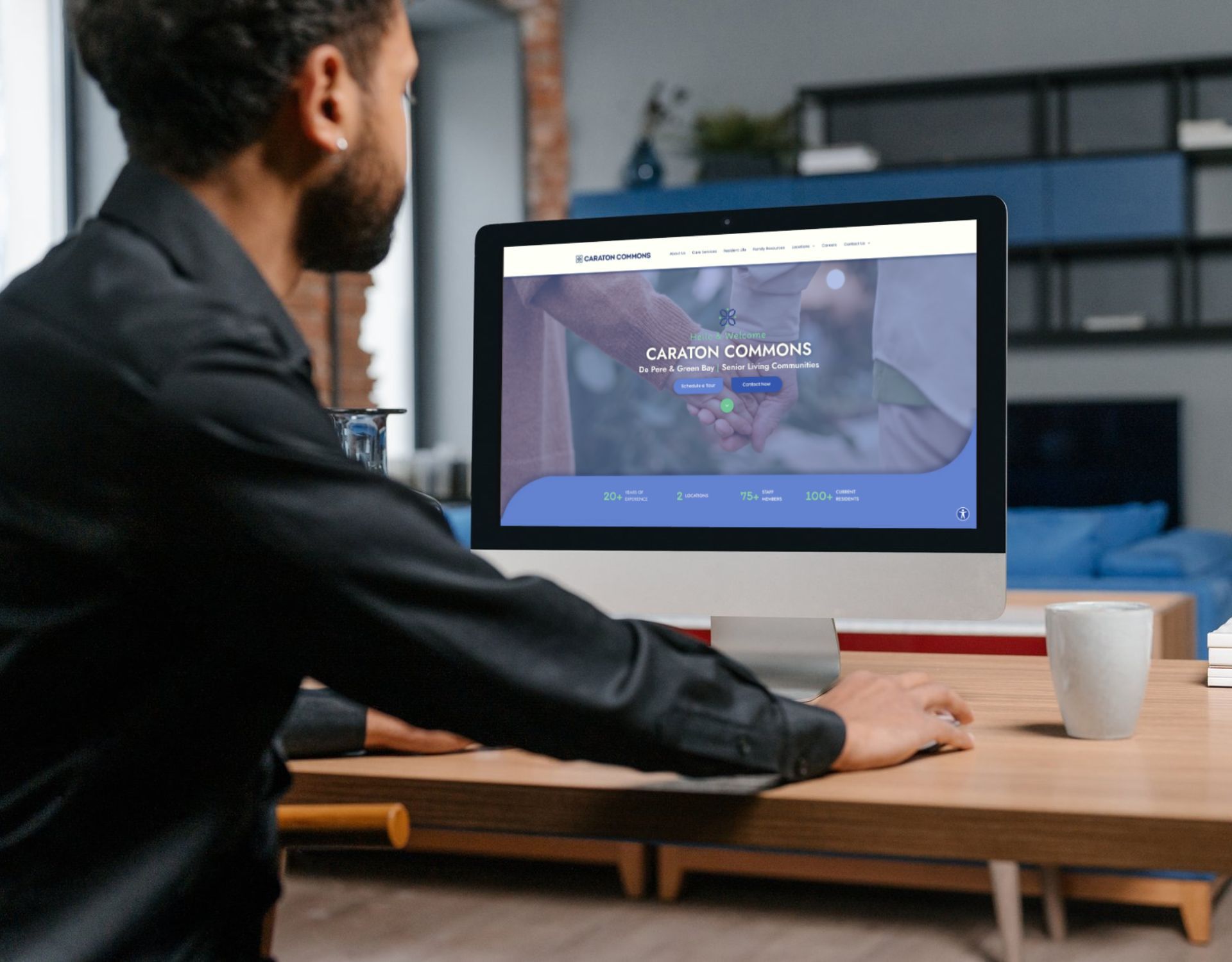 A man is sitting at a desk looking at a computer screen.