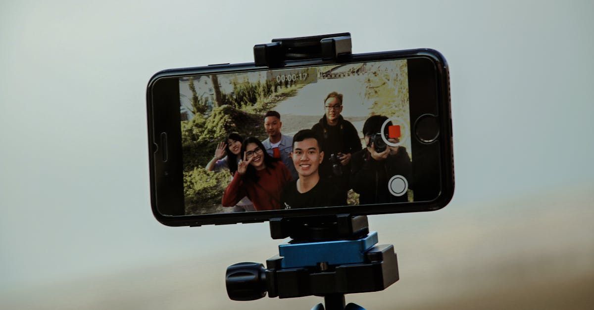A group of people are taking a selfie with a cell phone on a tripod.