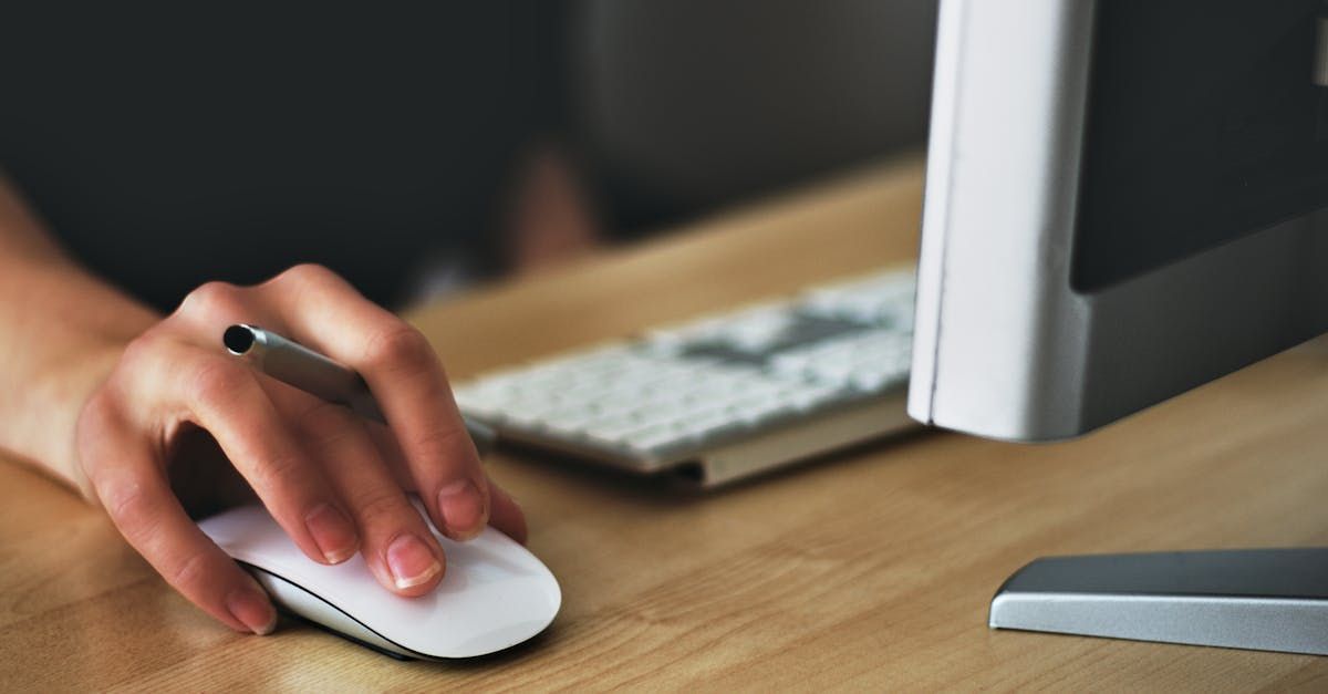 A person is using a computer mouse and writing on a keyboard.