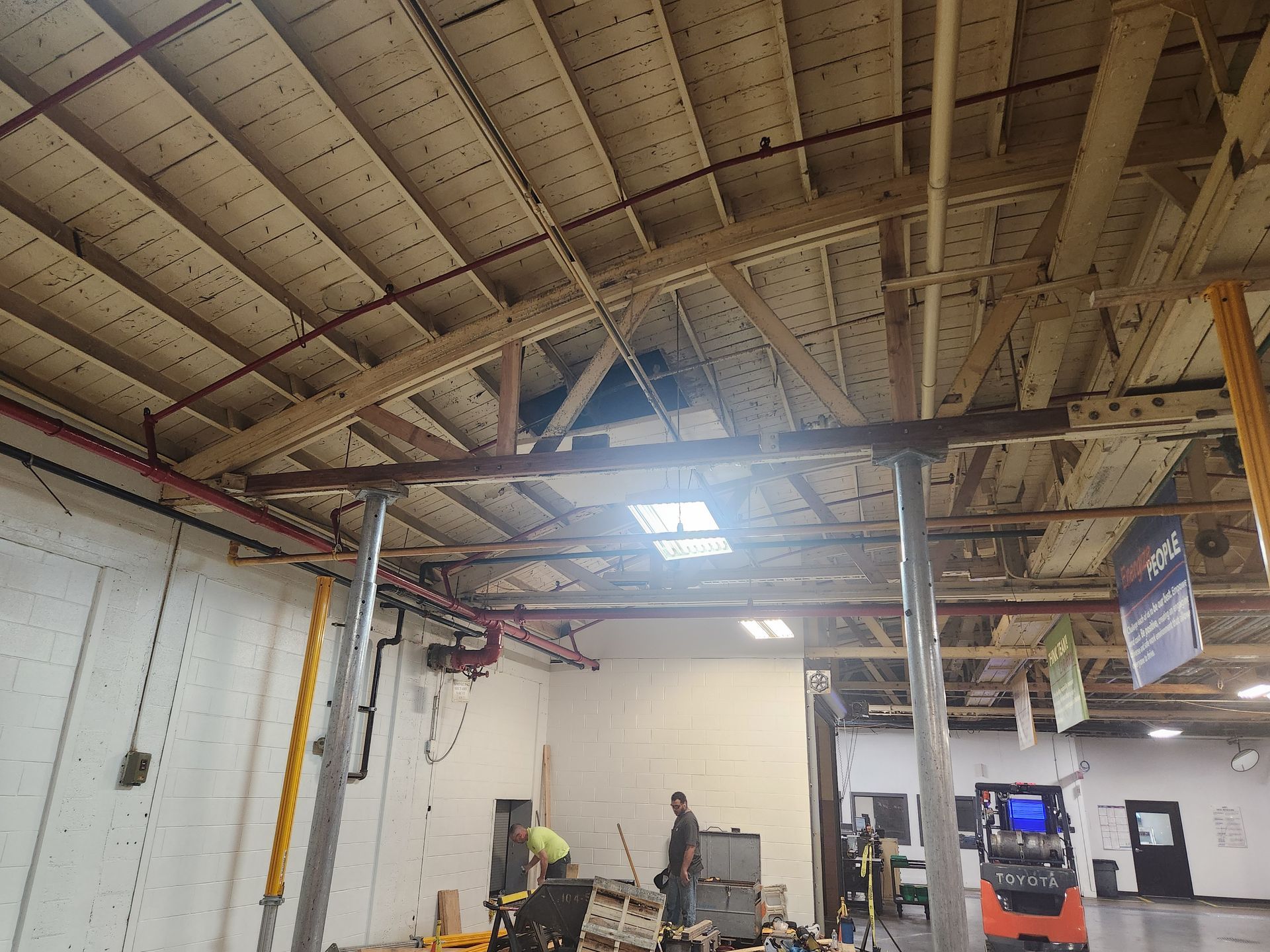 Workers repairing a warehouse with a bowstring truss roof, a Toyota forklift in Milwaukee, WI