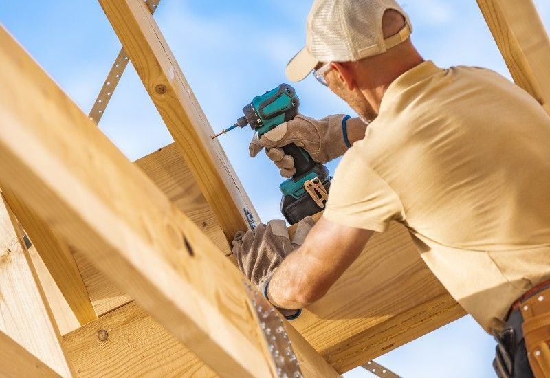 A worker drilling a wood truss, showing causes, issues & risks of collapse in Oshkosh & Milwaukee
