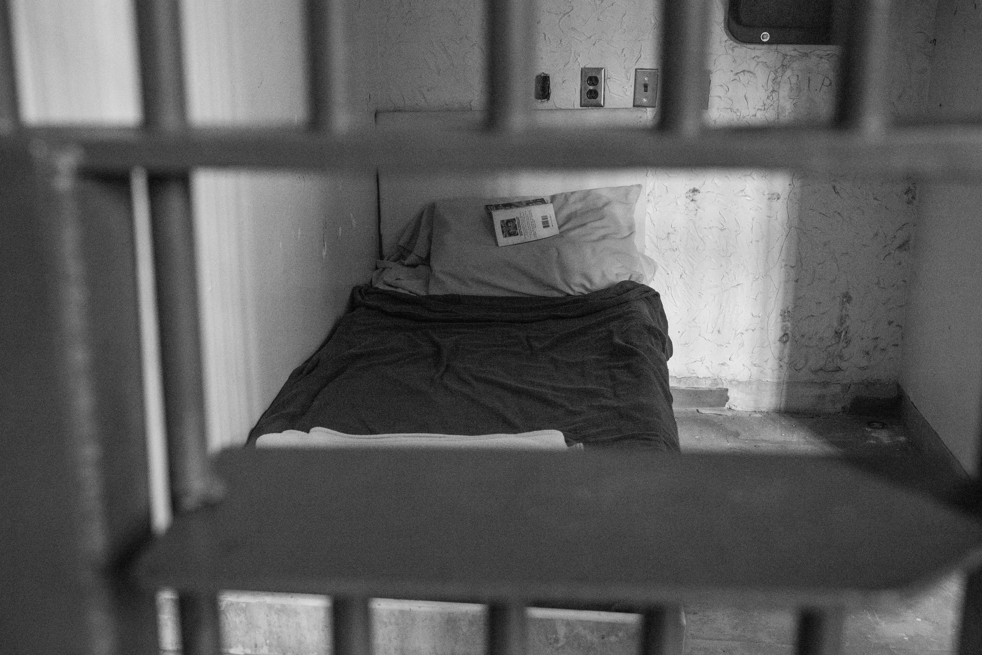 Dim prison cell with a bed and bars in the foreground