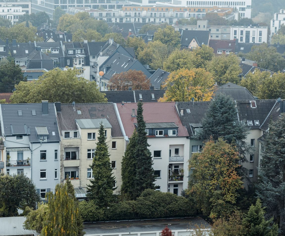 Blick auf Dächer und Bäume in einem Wohngebiet an einem bewölkten Tag.