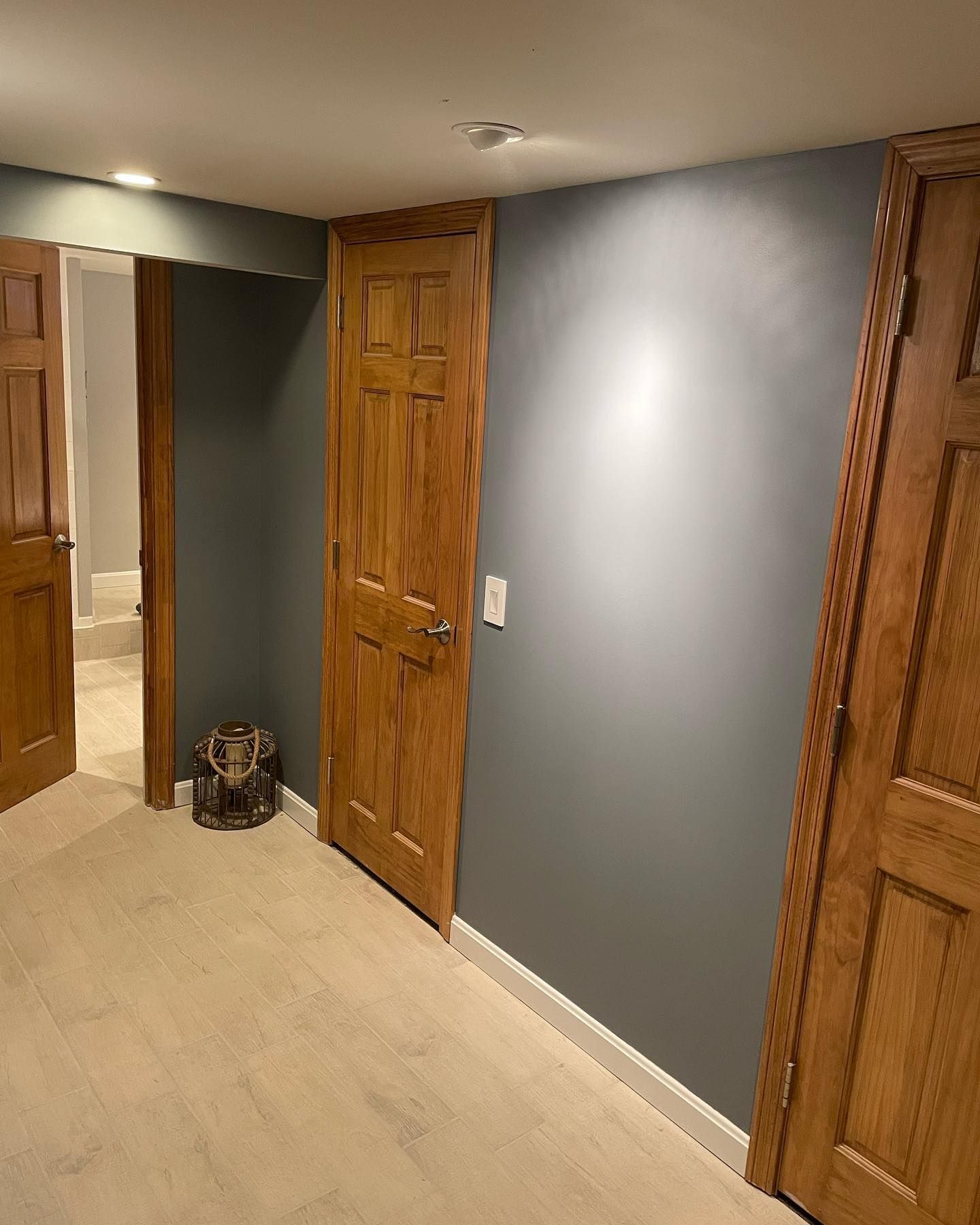 Interior view of a room with three wooden doors, gray walls, and light-colored flooring.