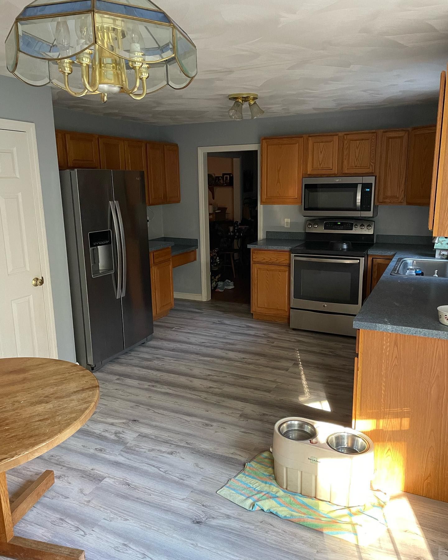 Kitchen with wooden cabinets, stainless steel appliances, gray walls, and light wood flooring.