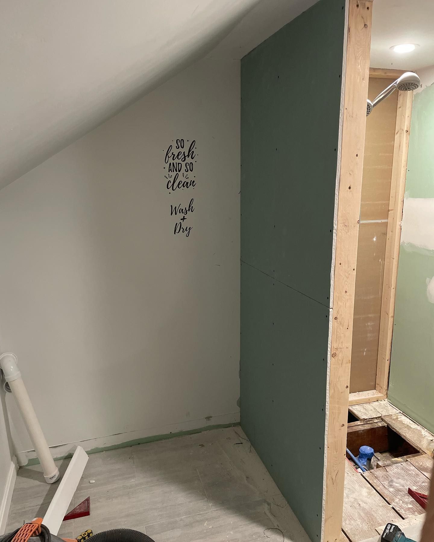 Interior view of a room under construction, with a slanted white wall and a green wall section.