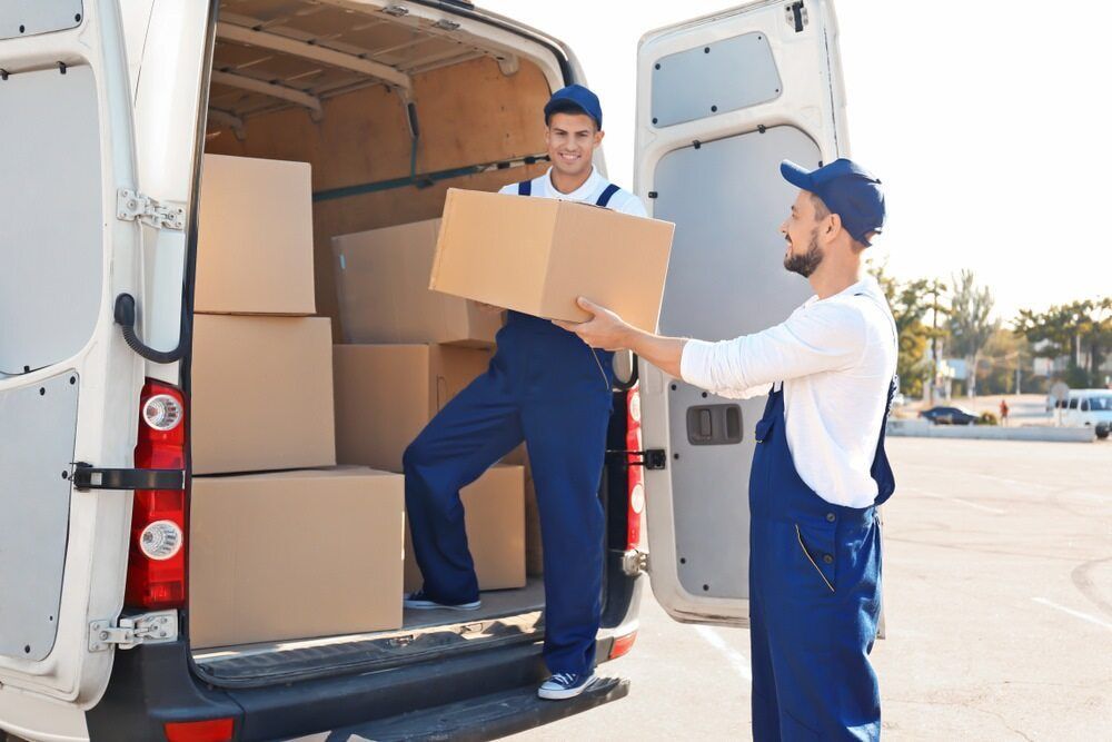 Two Delivery Men Are Loading Boxes Into a Van — FNQ Furniture Removals in Cairns, QLD