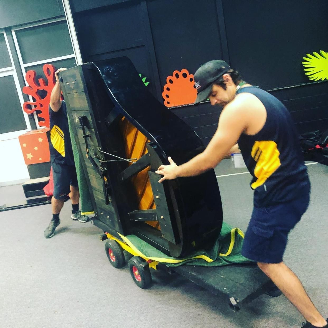 Two Men Are Moving a Piano on a Cart — FNQ Furniture Removals in Stratford, QLD