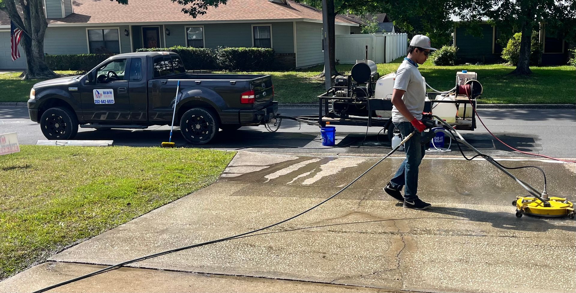 A man is using a pressure washer to clean a sidewalk.