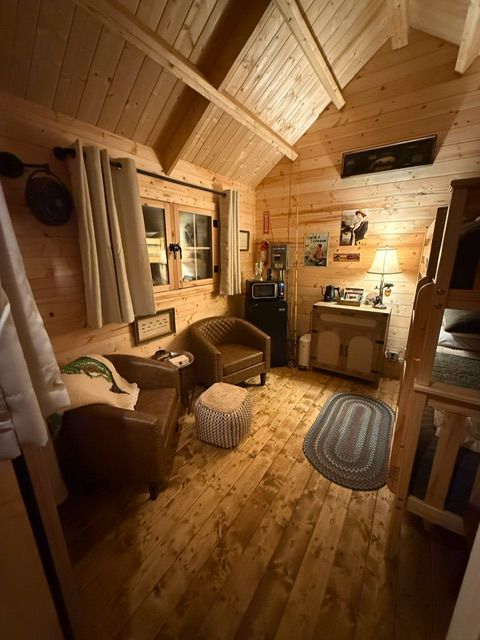 Cozy wooden cabin interior with a chair, rug, cabinet, window, and warm ambient lighting