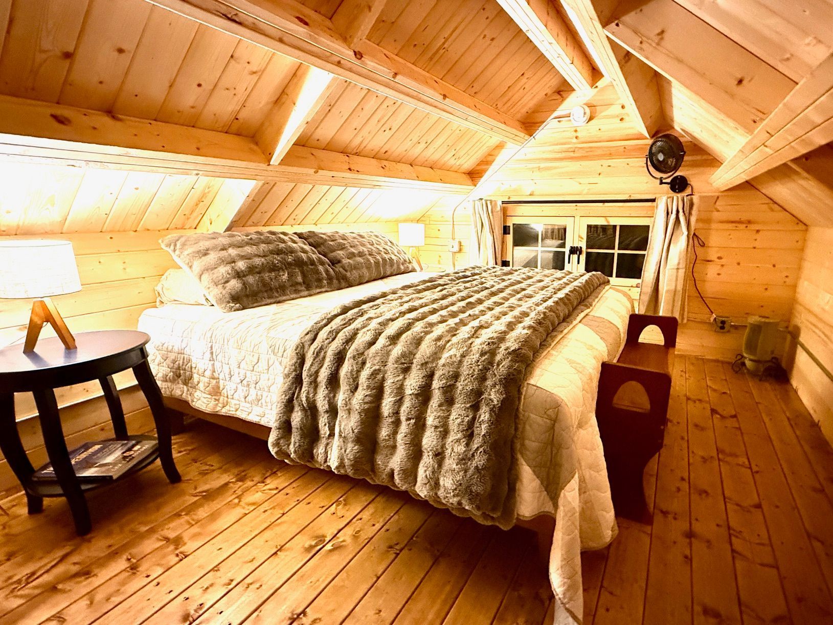 Cozy attic bedroom with wooden beams, twin beds, and warm sunlight through windows