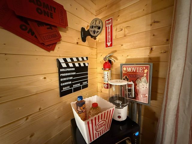Countertop popcorn machine in a small wooden room with retro movie decor and red poppin corn box.