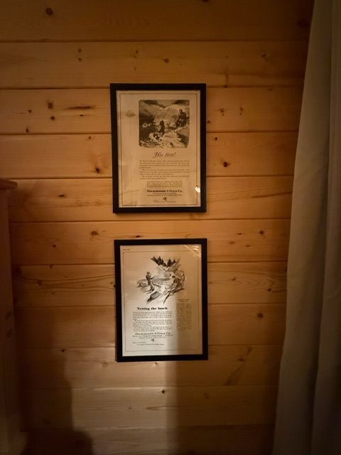 Two framed certificates on a wooden wall, lit by warm indoor light.
