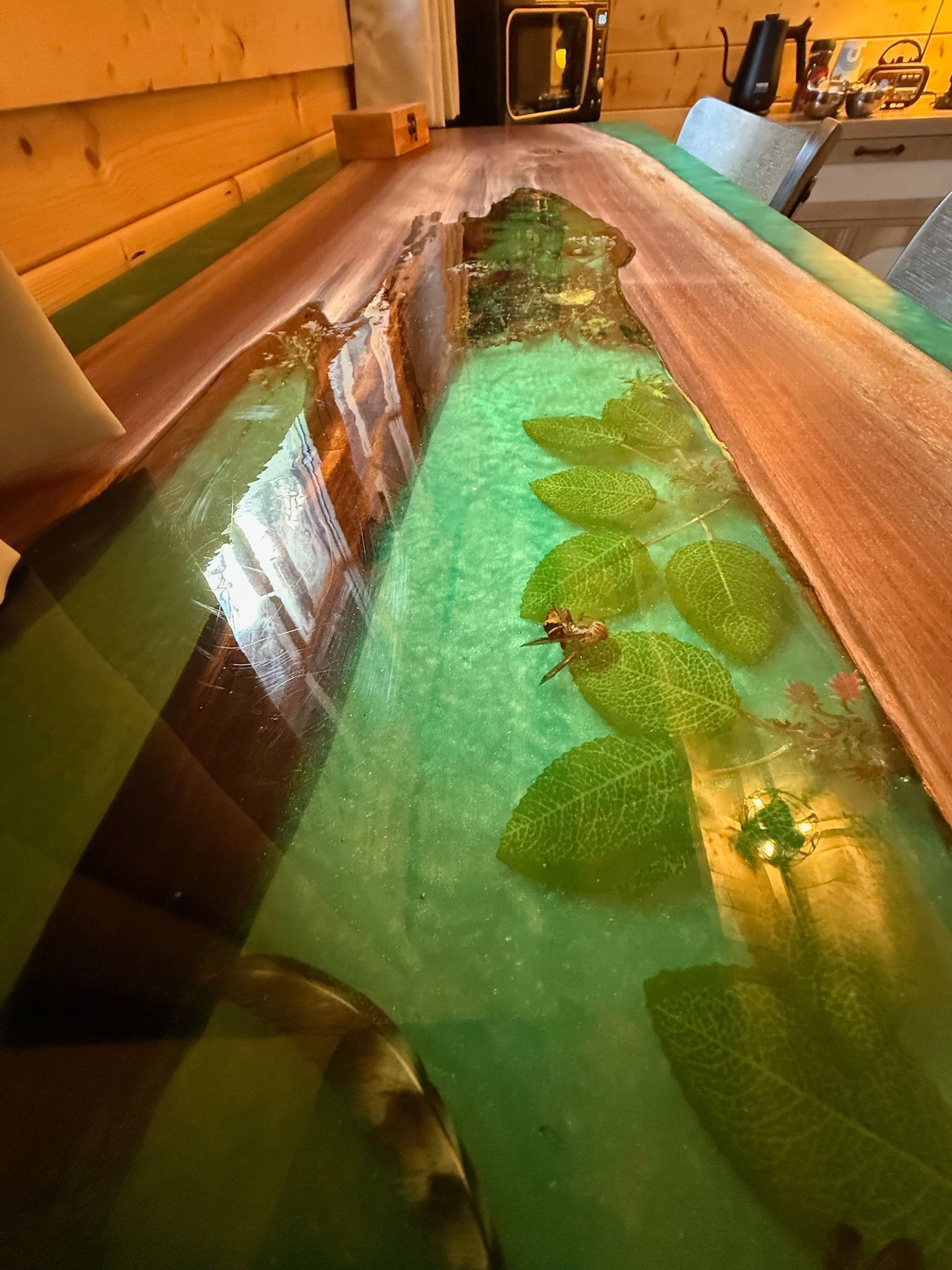 Long wooden water channel with green-lit water and leaf-like decorations indoors