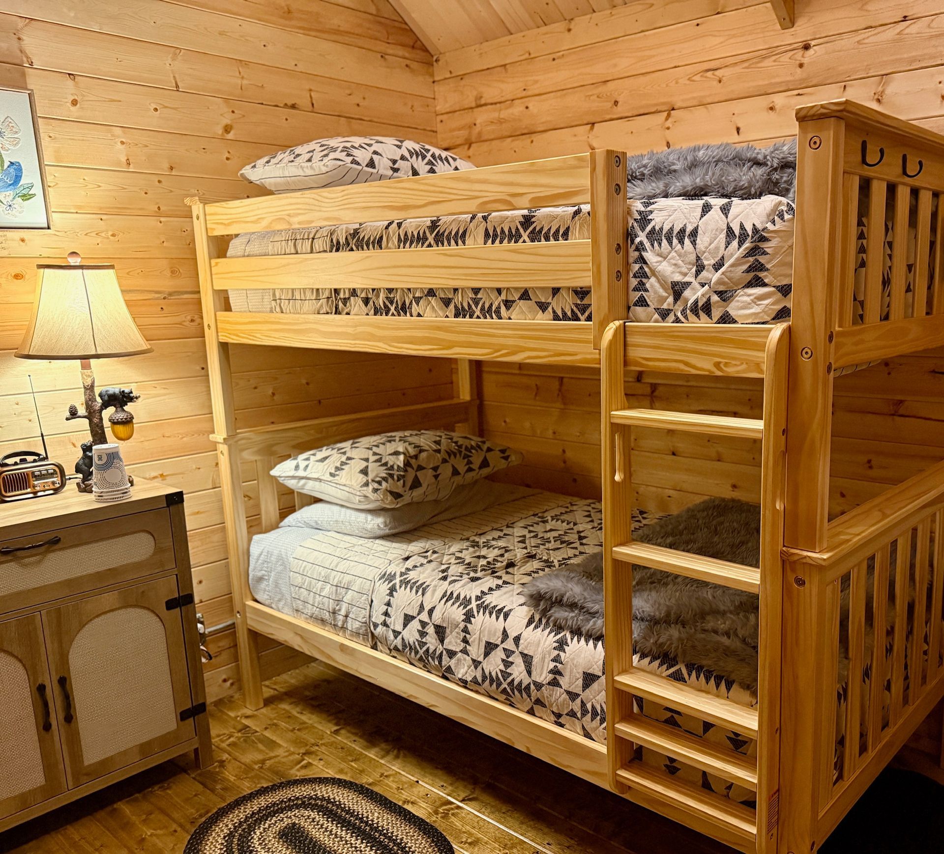 Wooden bunk bed in a cozy log cabin bedroom with plaid bedding and warm lighting