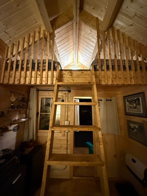 Loft ladder in a cozy wooden attic room with exposed beams and warm lighting
