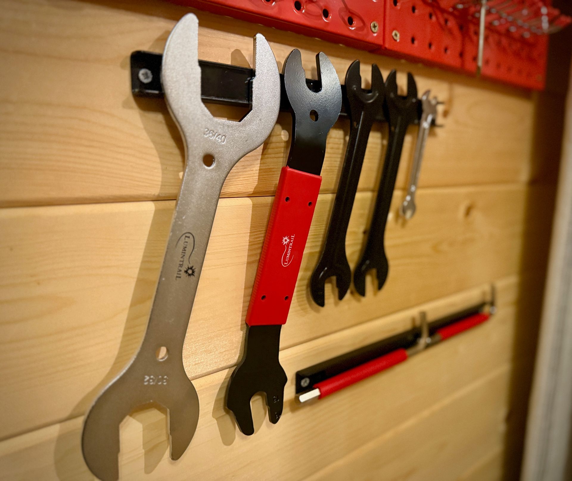 Wrenches and hand tools hanging on a wooden workshop wall rack