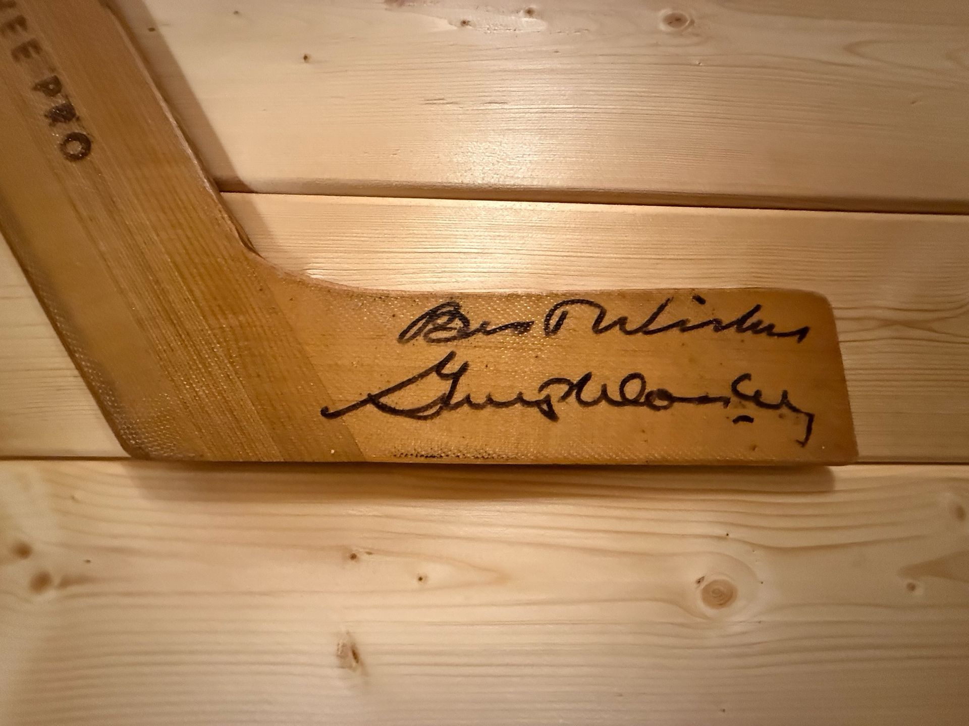 Wooden panel with a black handwritten signature on the lower right.