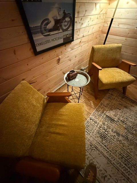 Cozy seating nook with yellow chairs, small round table, wood-paneled wall, and warm lighting
