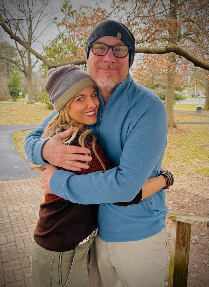 Two people hugging outdoors in fall, smiling and wearing cozy winter clothes.