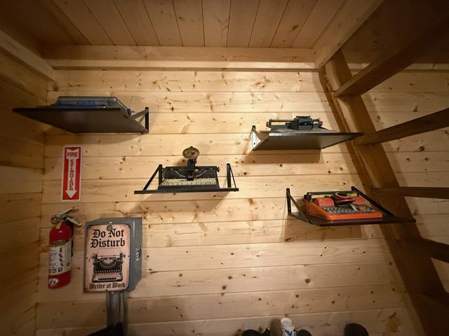 Wood-paneled room with wall-mounted shelves holding small model cars and a fire extinguisher
