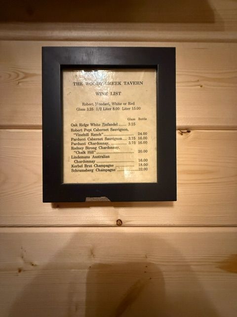 Framed menu board on a wood-paneled wall with a light shining above it
