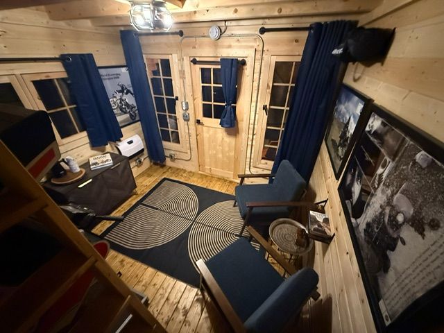Cozy wood-paneled room with blue chairs, rug, curtains, and a black-and-white wall photo