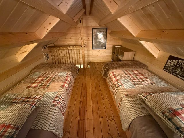 Attic bedroom with two twin beds, wood-paneled walls, and a sloped ceiling