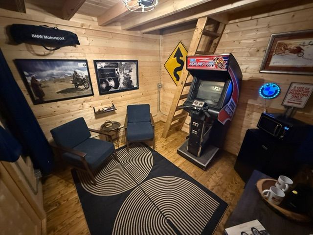 Rustic room with two chairs, framed photos, a jukebox, and patterned rugs