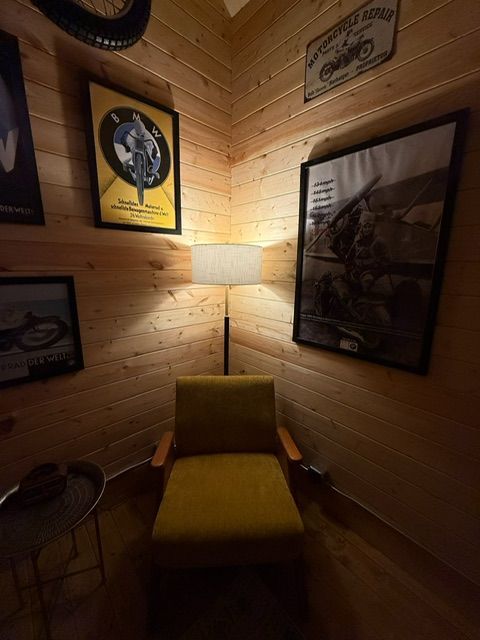Cozy wood-paneled corner with a yellow chair, floor lamp, and framed wall art.