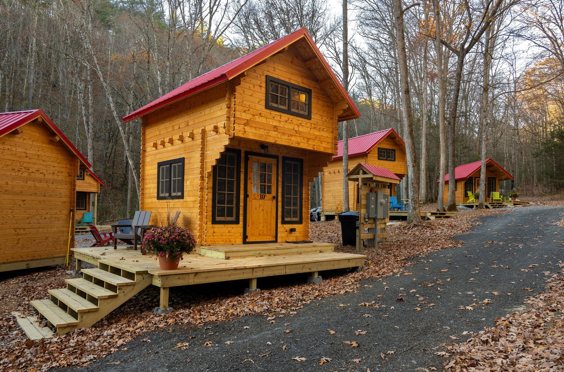 Small wooden cabins with red roofs along a gravel road in an autumn forest